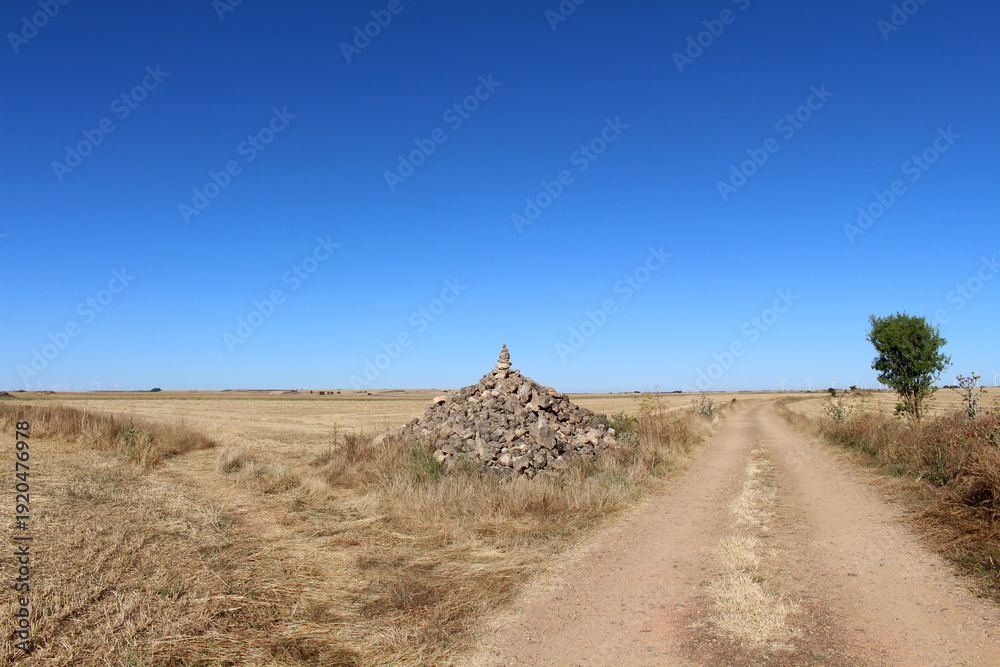 Fototapeta premium Dirt path and stacked stones near Hornillos del Camino in 2024