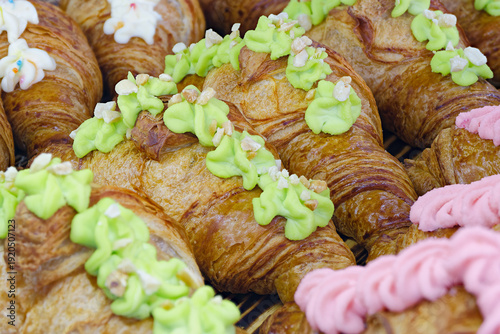 Traditional croissants decorated with green, pink, and white buttercream