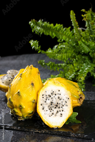 Fresh Yellow Dragon Fruit Halves on Slate - Exotic Tropical Pitaya with Seeds and Fern Decoration