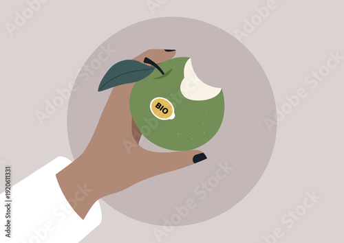 A hand holds a freshly bitten green apple, adorned with a bio label, capturing the essence of healthy living and mindful eating, The background complements the apple's natural beauty