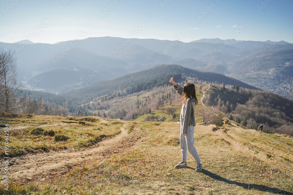 Obraz premium Woman pointing toward mountains on scenic trail