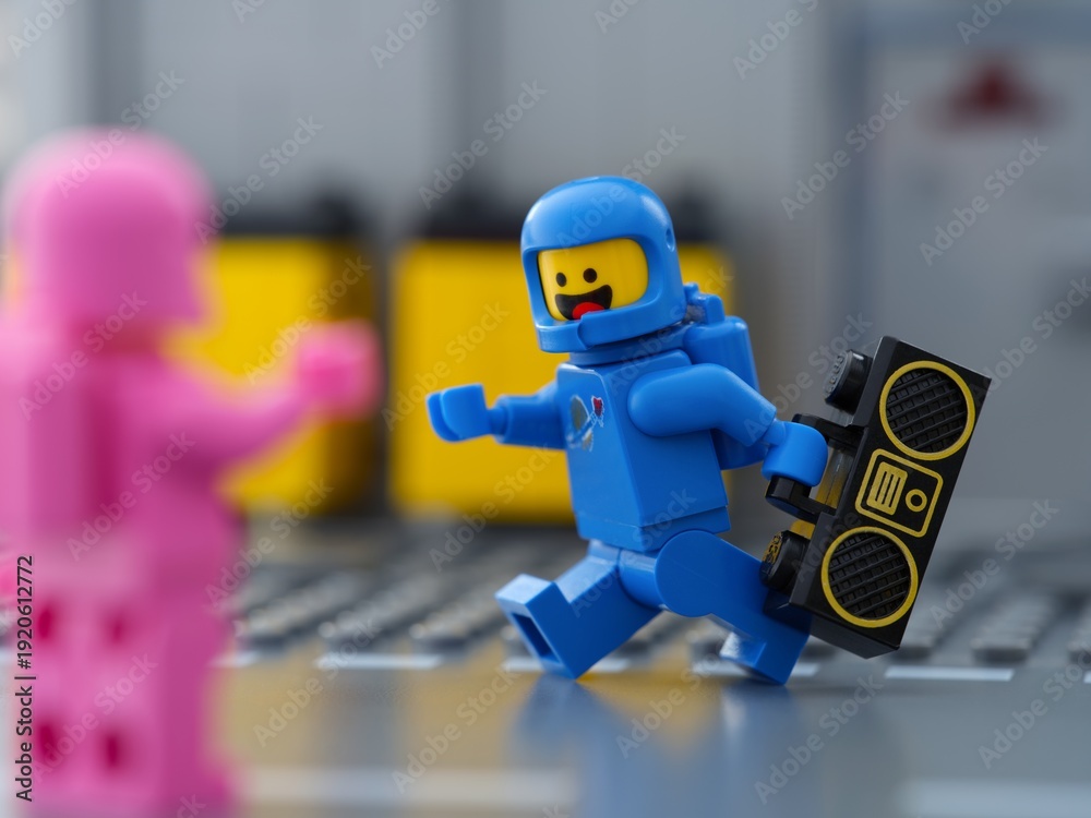 Fototapeta premium Tambov, Russian Federation - May 30, 2025 A cheerful blue Lego astronaut minifigure running with a boombox towards a pink companion.