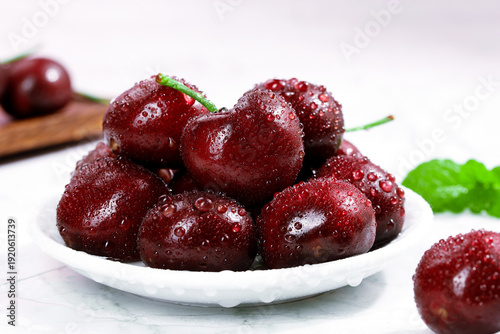 Fresh Wet Dark Red Cherries on White Plate with Mint Garnish