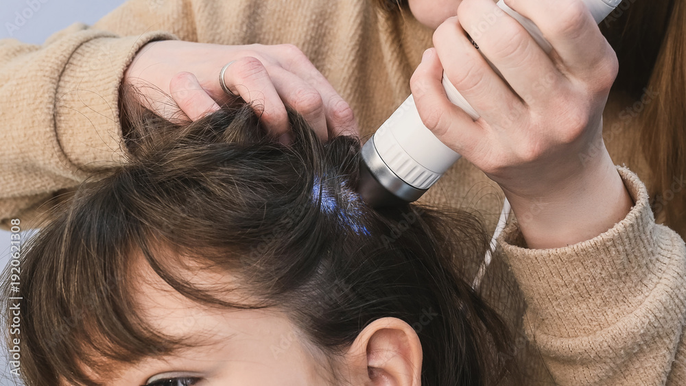 Fototapeta premium Trichologist examines hair and scalp of young woman in salon using trichoscope and dermatoscope. Woman's hair loss, dandruff and oily hair problems, scalp treatment and hair care consultations 