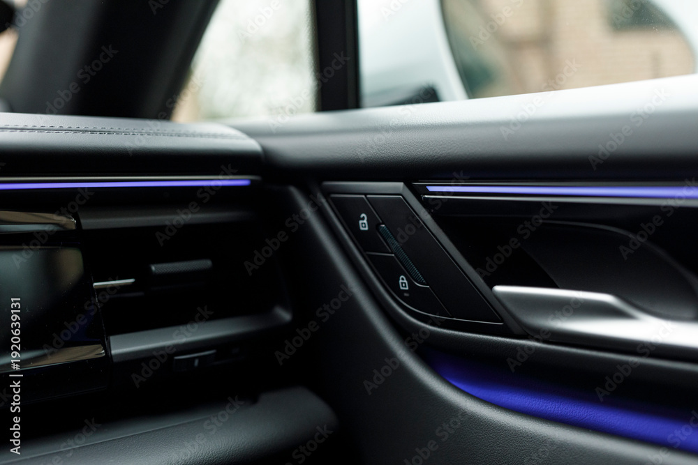 Naklejka premium Close-up shot of a car door handle with illuminated accents. Focus on luxury design and detail, sleek dashboard aestheti