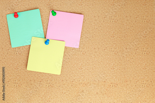 Colorful assortment of pinned sticky notes on cork board background. Organizational aids for reminders and tasks, perfect for office or educational use. Simple and effective method for notes