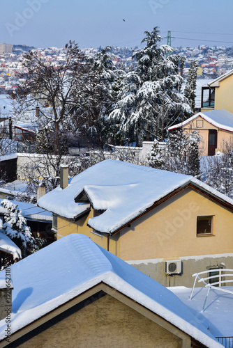 Yellow house with roof covered in deep, fresh white snow