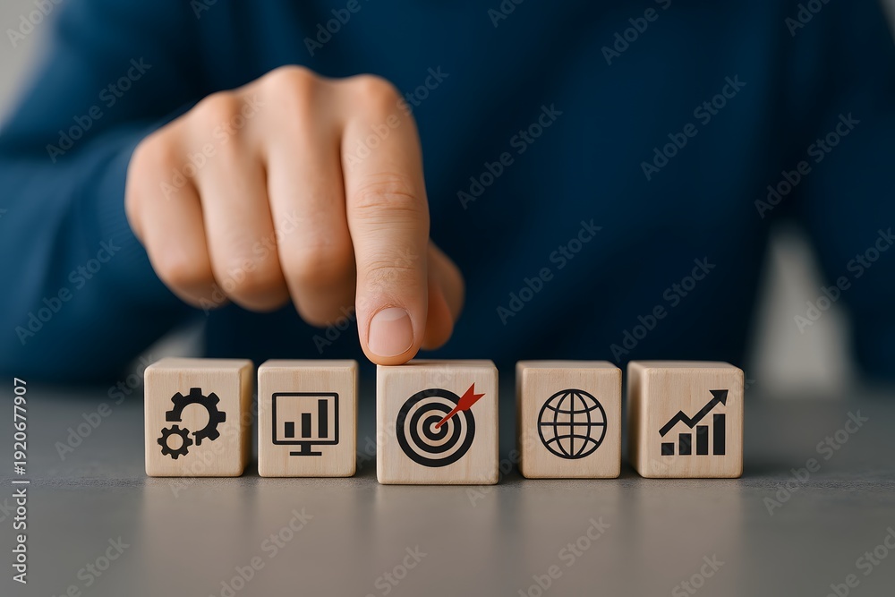 Naklejka premium Hand points to a wooden block with a target icon, emphasizing business goals and focused achievement.