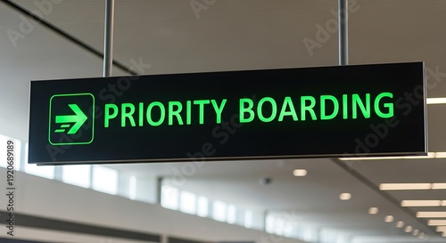 Green illuminated priority boarding sign with airplane icon at airport image photo