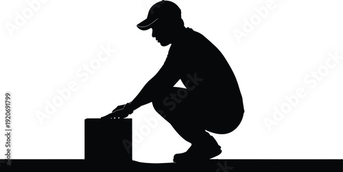 Man in baseball cap crouches beside a box silhouette black white background