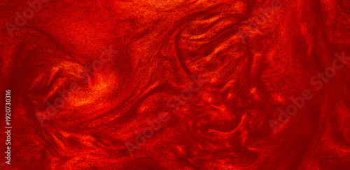 Shimmering red abstract background. Liquid glitter paint texture waves and swirls. Beautiful shiny red glitter texture. Metallic paint close-up as a holiday background.