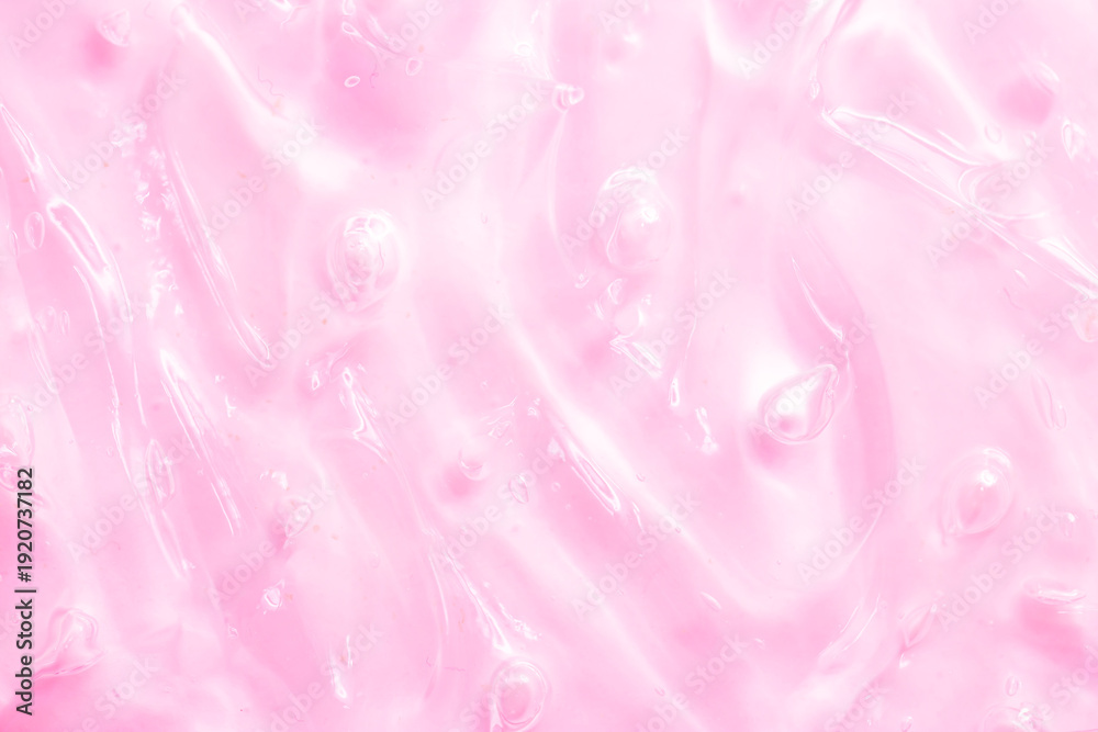 Fototapeta premium Cosmetic gel, serum, clear sample with a pink tint, close-up. Liquid cream with a foaming texture. Gel-like texture of a cosmetic product. Liquid cosmetic lotion for skin care.