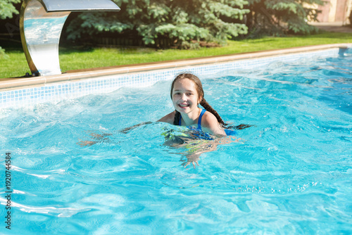 Teen girl swimming in pool. Kids splashing in pool. Children fun and rest by the pool in summer. Playful outdoor activity for children.