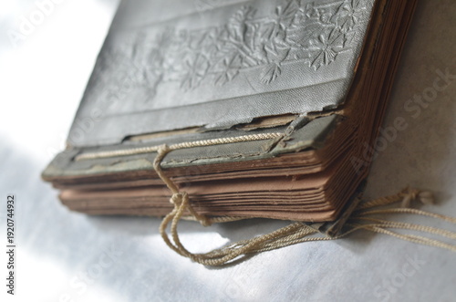 Vintage photo album with old photographs and cord tie, nostalgic memory concept, soft light, shallow depth of field.