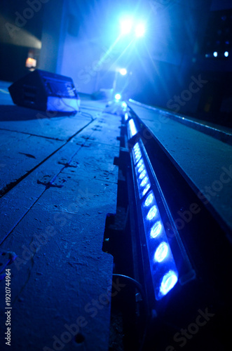 Blue stage LED lights along theater floor with dramatic perspective and lens flare, concert lighting equipment, low angle view, performance atmosphere.