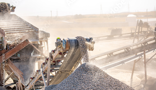 Vibrating screen stone crusher in operation. Crushing stones in a quarry for processing minerals, cement, limestone. Heavy and mobile equipment in a quarry for processing stone into building material.