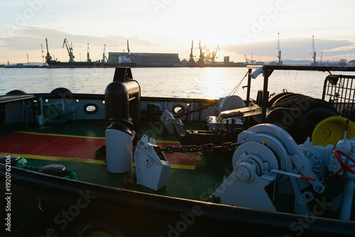View from a ship deck with anchor winch and heavy chains towards the industrial port of Burgas, Bulgaria at sunset