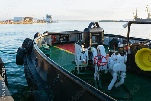 View from a ship deck with anchor winch and heavy chains towards the industrial port of Burgas, Bulgaria at sunset