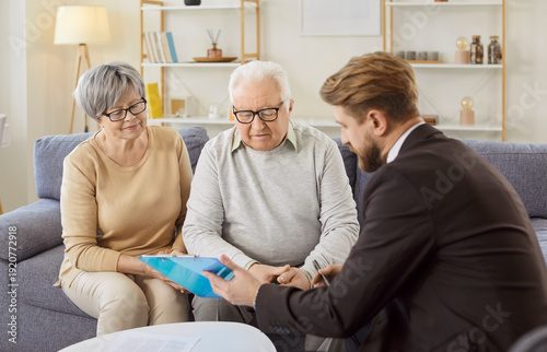 Foto Young man financial advisor, broker, or agent explains contract details, legal agreement terms to elderly wife and husband, before signing