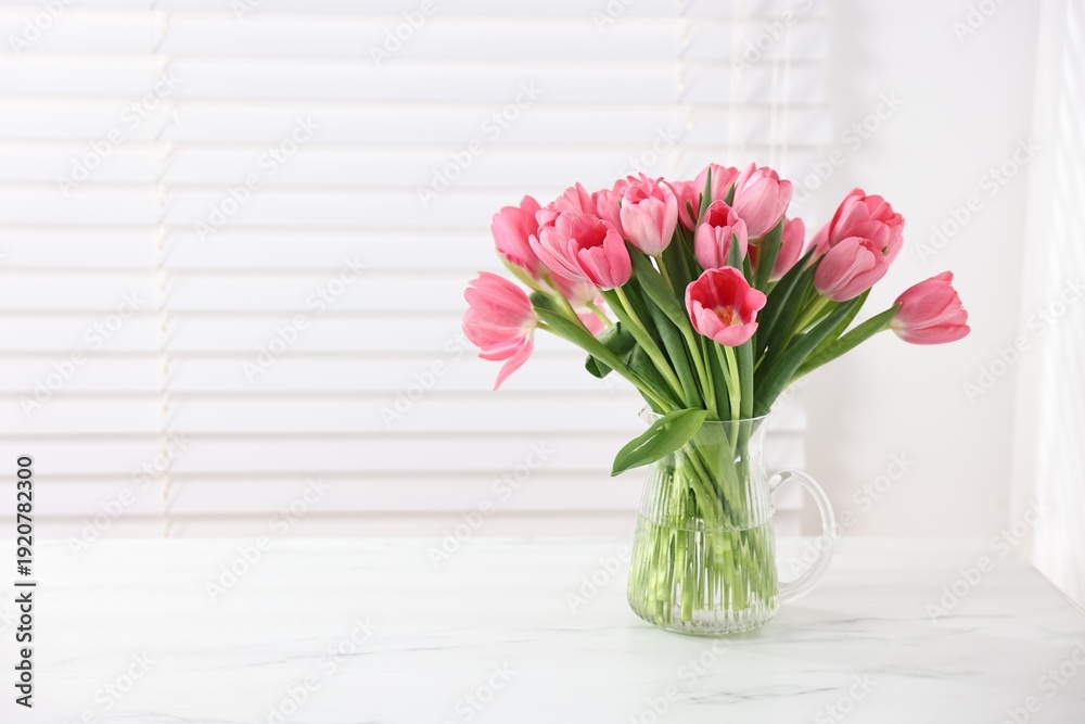 Fototapeta premium Bouquet of pink tulips in vase on white marble table. Space for text