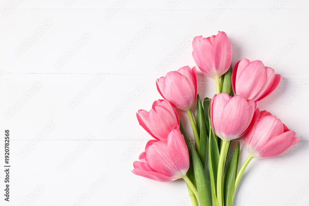 Fototapeta premium Bouquet of pink tulips on white wooden table, top view. Space for text