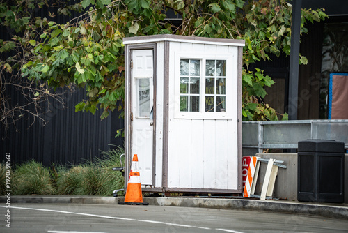 Φωτογραφία Small white security guard booth with an open door and a traffic cone outside