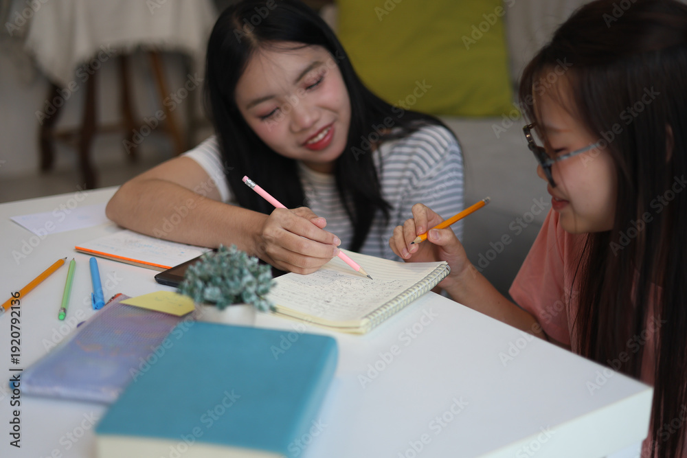 Fototapeta premium Two teenage girls writing in notebooks while studying at home.