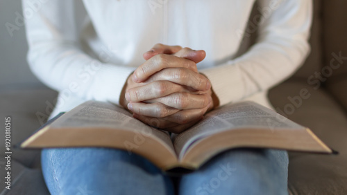 Foto close up of woman praying with hands clasped over open bible at home, christian