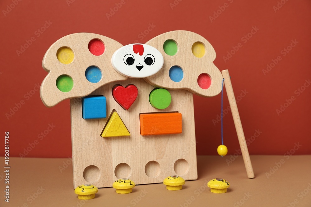 Obraz premium Magnetic sorting set for children with wooden hen, figures and fishing rod on beige table against brown background, closeup