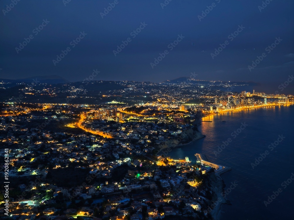 Obraz premium Night view shows coast. Nighttime aerial shot highlights brightly lit seaside settlements along roads