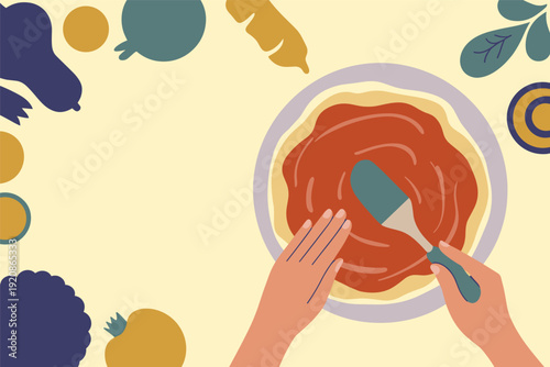 Hands spreading tomato sauce on pizza dough with colorful vegetables around