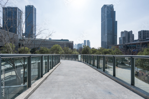 Konstfotografi Modern urban pedestrian bridge connecting high-rise buildings with greenery and