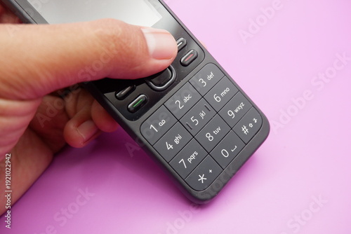 Hand Holding Classic Keypad Mobile Phone on Purple Background