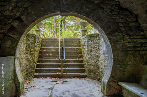 Fényképezés Stone archway frames mossy steps leading from Grotto Spring to the forest view