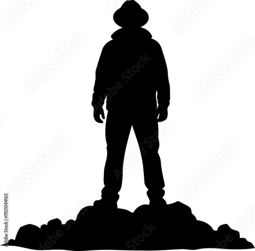 Adventurer silhouette standing on a rocky peak wearing a hat