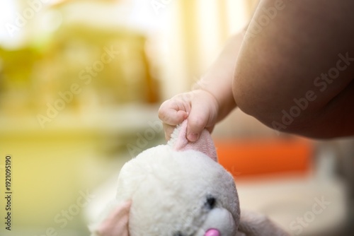 Wallpaper Mural Child's hand, supported by mother, holding a soft cat toy by its pink ear. Tender parenting moment. Torontodigital.ca