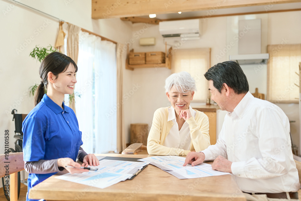 Obraz premium 訪問介護でプランの説明をするアジア人介護士