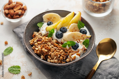 Homemade crispy granola, yogurt, fruits and berries in bowl on white background. Healthy breakfast