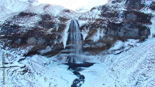 Snowy mountain waterfall in winter landscape.