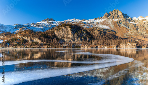 Foto Panorama of the frozen lake with curvy opaque ice line on the Silsersee Lake in St