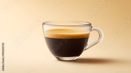Close up of a freshly brewed rich dark coffee drink with golden crema in a clear glass cup, isolated against a simple, warm beige background