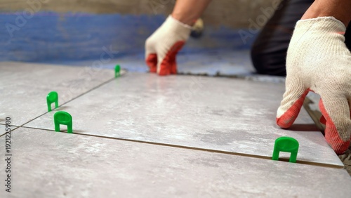 Worker installing floor tiles using tile spacers