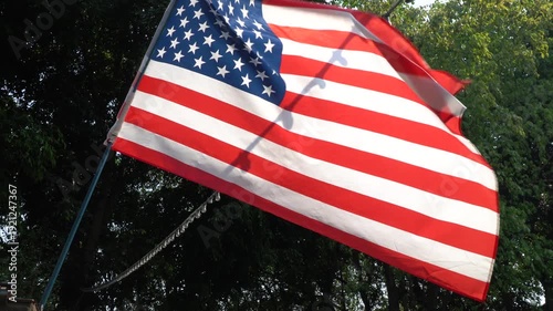 American flag waving against a backdrop of green trees