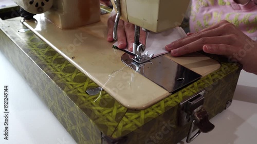 woman seamstress sews a white fabric on an electric sewing machine.