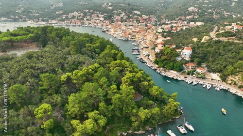 Wide Aerial Shot of Paxos Island Capital Gaios Showing the Protected Natural Harbor Channel Lush Vegetation and Coastal Cityscape under a Summer Sky