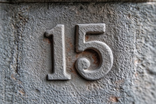embossed number 15 on a weathered rough stone plaque with rust stains and textured gray surface, evoking a timeworn, aged feel