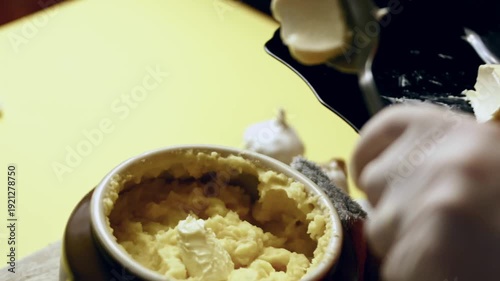 Person adds butter to mashed potatoes to enrich the flavor and texture