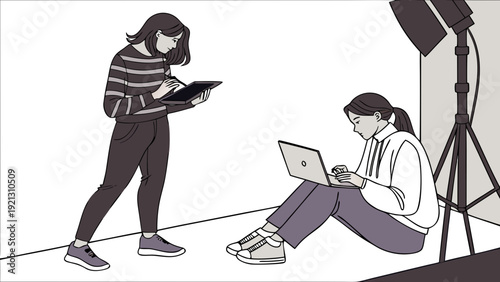 Two women working together in a studio setting with a laptop and a folder focused on their tasks.