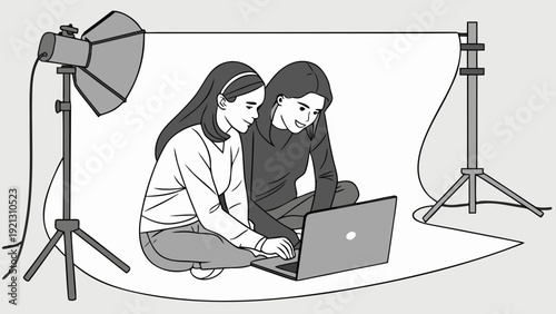 Two young women using a laptop in a photo studio setup.