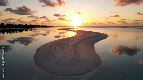 Tranquil lagoon at sunset with sandy beach and colorful clouds reflecting on calm waters, showcasing a peaceful coastal scene